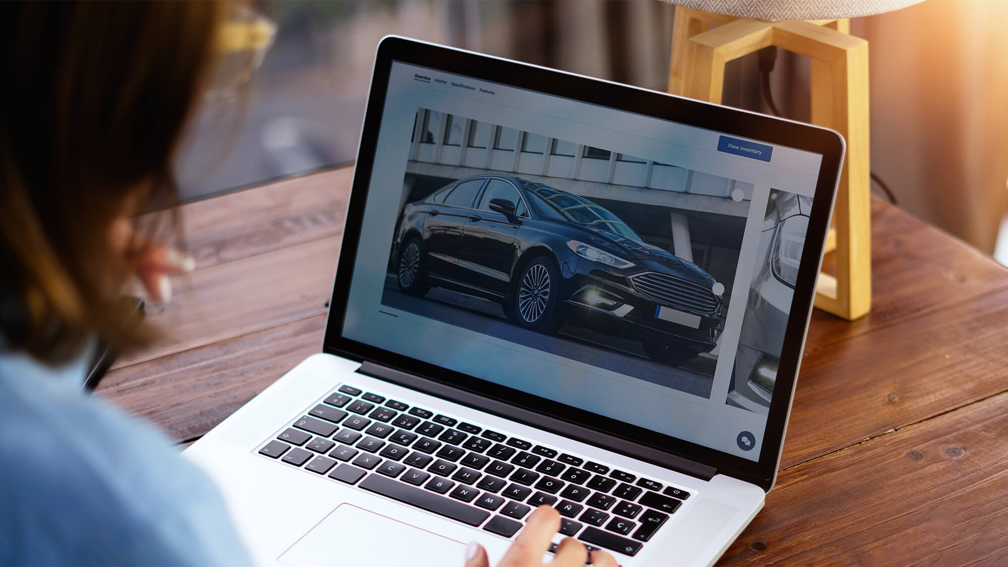 A person views images of a black car on a laptop screen.