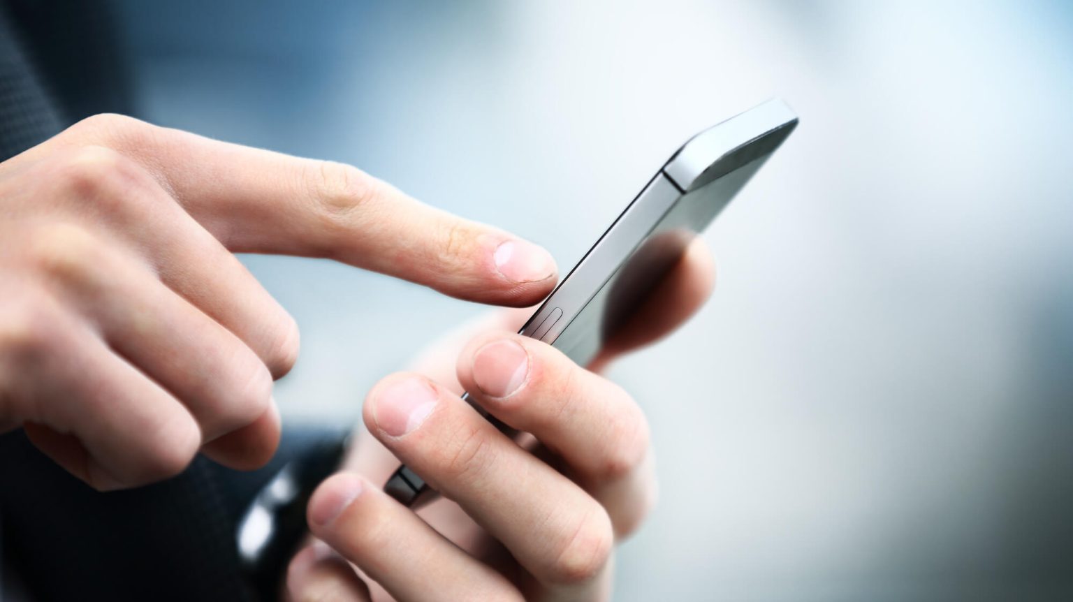 Close-up of a person using a smartphone, with one hand holding the device and the other hand touching the screen.